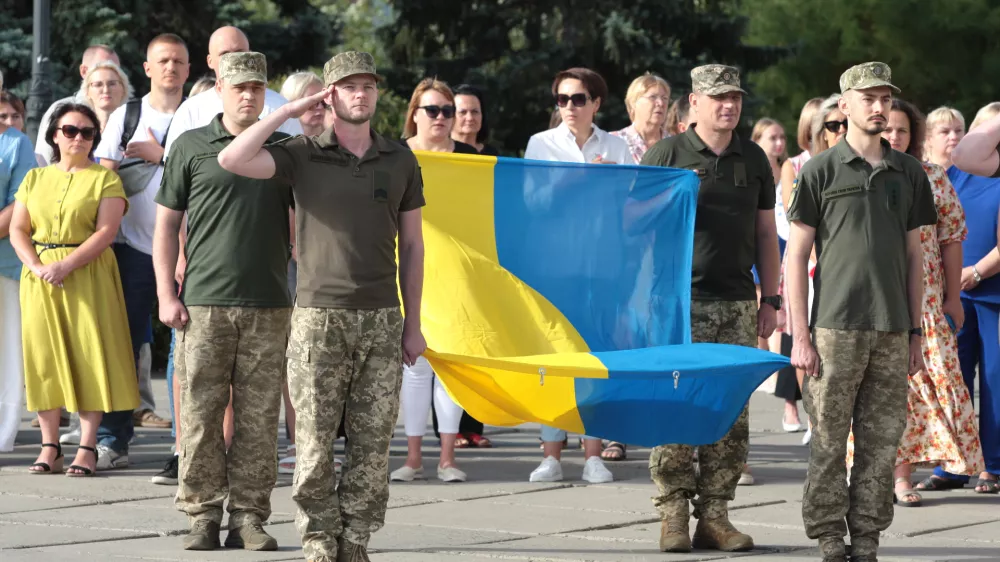 23 August 2024, Ukraine, Kiev: Soldiers stand to attention with the national flag outside the Densianskyi District State Administration on State Flag Day. Photo: -/Ukrinform/dpa