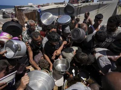 Displaced Palestinians at a food distribution center in Deir al Balah, central Gaza Strip, Friday, Aug. 23, 2024. (AP Photo/Abdel Kareem Hana)