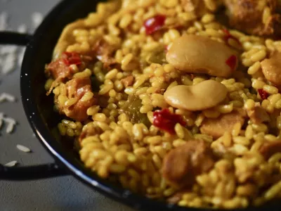 closeup of a typical spanish paella valenciana in a typical paella pan, on a gray rustic surface / Foto: Nito100