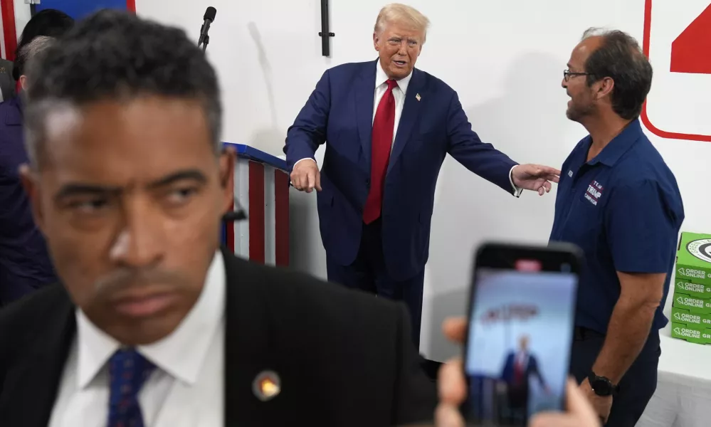 Republican presidential nominee former President Donald Trump, center, speaks with a supporter during a stop at a campaign office, Monday, Aug. 26, 2024, in Roseville, Mich. (AP Photo/Carolyn Kaster)