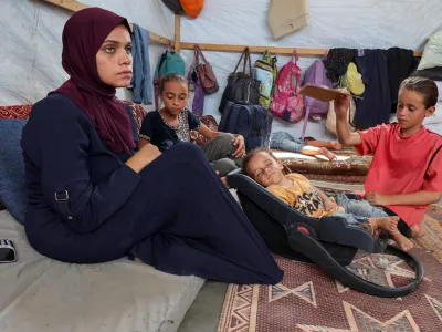 Palestinian boy Abdul Rahman Abu Al-Jidyan, who is the first person to contract polio in Gaza in 25 years, is fanned by his sister as his mother sits in their tent, in Deir Al-Balah, in the central Gaza Strip August 28, 2024. REUTERS/Ramadan Abed