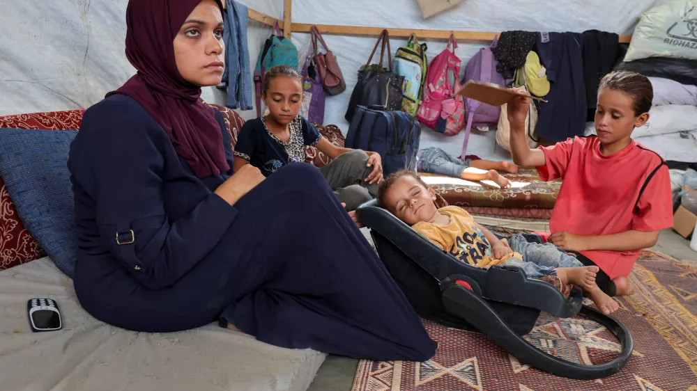 Palestinian boy Abdul Rahman Abu Al-Jidyan, who is the first person to contract polio in Gaza in 25 years, is fanned by his sister as his mother sits in their tent, in Deir Al-Balah, in the central Gaza Strip August 28, 2024. REUTERS/Ramadan Abed