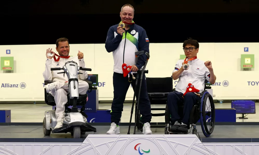 Paris 2024 Paralympics - Shooting - R4 - Mixed 10m Air Rifle Standing SH2 Final - Chateauroux Shooting Centre, Deols, France - August 30, 2024 Gold medallist Francek Gorazd Tirsek of Slovenia celebrates on the podium after the final with silver medallist Tanguy de La Forest of France and bronze medallist Huntae Seo of South Korea REUTERS/Eng Chin An