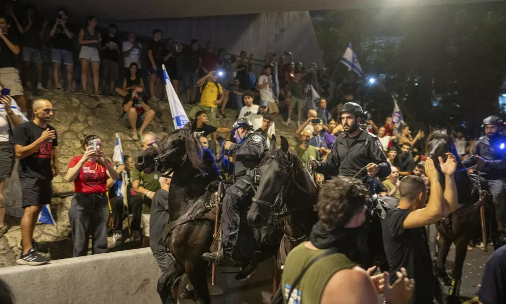 People protest, calling for a deal for the immediate release of hostages held in the Gaza Strip by Hamas, as law enforcement on horses respond in Tel Aviv, Israel, Sunday, Sept. 1, 2024. (AP Photo/Ohad Zwigenberg)