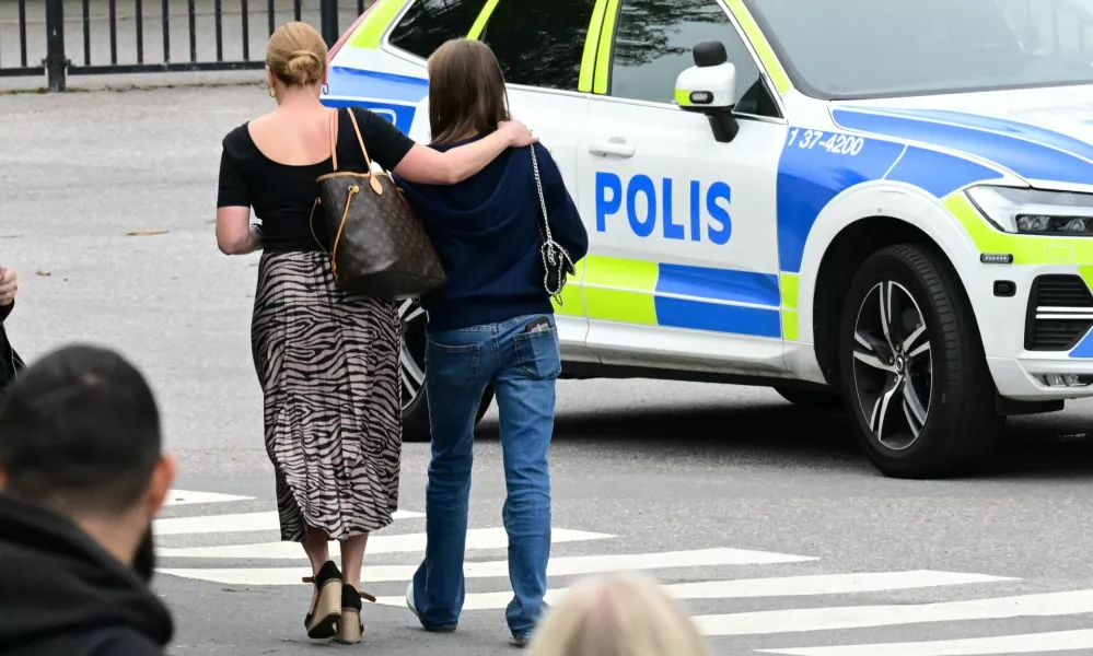 People walk next to a police vehicle following a shooting incident in Trangsund, Huddinge, Sweden September 4, 2024. TT News Agency/Jonas Ekstromer/via REUTERS   ATTENTION EDITORS - THIS IMAGE WAS PROVIDED BY A THIRD PARTY. SWEDEN OUT. NO COMMERCIAL OR EDITORIAL SALES IN SWEDEN.