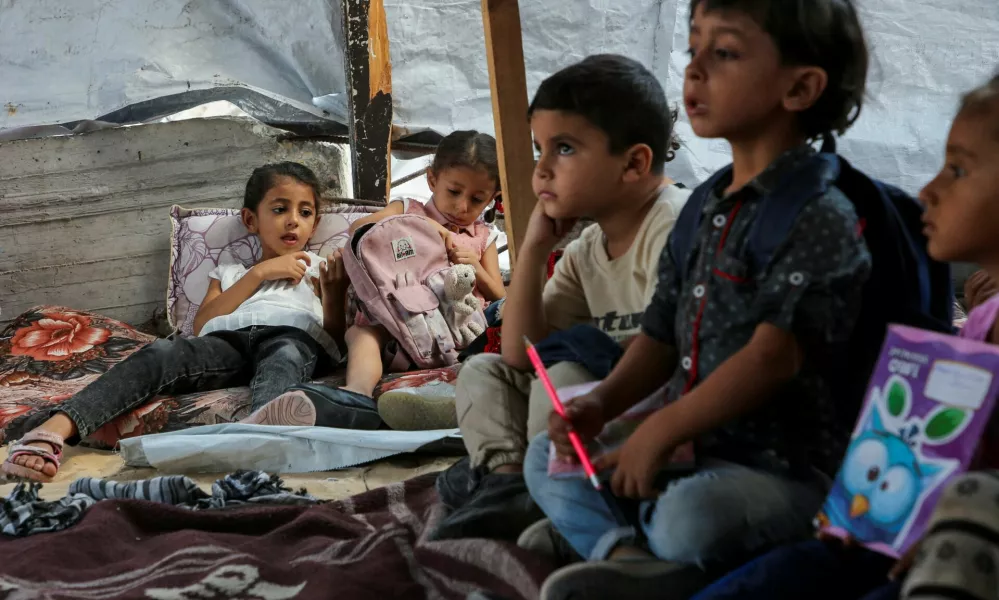 Palestinian students attend a class in a tent set up on the rubble of the house of teacher Israa Abu Mustafa, as war disrupts a new school year, amid the Israel-Hamas conflict, in Khan Younis, in the southern Gaza Strip, September 4, 2024. REUTERS/Hatem Khaled   TPX IMAGES OF THE DAY