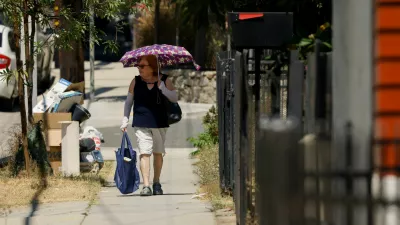 A pedestrian walks with an umbrella to protect her skin from the sun during a period of high weather temperatures in Los Angeles, California, U.S. September 5, 2024. REUTERS/Etienne Laurent