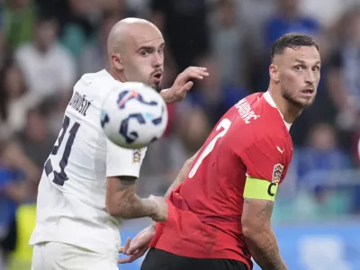 Slovenia's Vanja Drkusic, left, and Austria's Marko Arnautovic look at the ball during the UEFA Nations League soccer match between Slovenia and Austria at the Stozice stadium in Ljubljana, Slovenia, Friday, Sept. 6, 2024. (AP Photo/Darko Bandic)