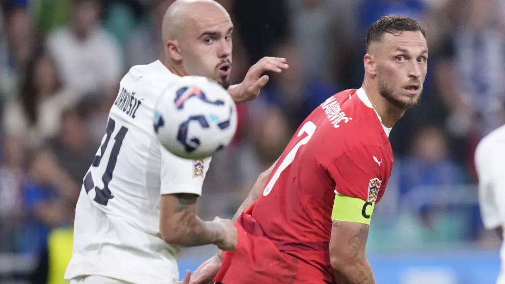 Slovenia's Vanja Drkusic, left, and Austria's Marko Arnautovic look at the ball during the UEFA Nations League soccer match between Slovenia and Austria at the Stozice stadium in Ljubljana, Slovenia, Friday, Sept. 6, 2024. (AP Photo/Darko Bandic)