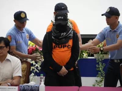 Apollo Quiboloy, center, a Filipino preacher accused of sexual abuse and human trafficking in the Philippines and similar charges in the United States, is escorted beside Philippine Secretary of Interior and Local Government Benhur Abalos, left, during a press conference at the Camp Crame police headquarters in Quezon City, Philippines Monday, Sept. 9, 2024. (AP Photo/Aaron Favila)