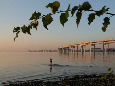 A man wades in the Gulf of Finland near the Western High-Speed Diameter (WHSD) highway during sunset in Saint Petersburg, Russia September 8, 2024. REUTERS/Anton Vaganov   TPX IMAGES OF THE DAY