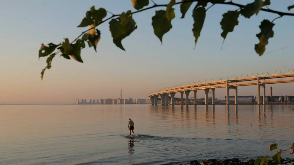 A man wades in the Gulf of Finland near the Western High-Speed Diameter (WHSD) highway during sunset in Saint Petersburg, Russia September 8, 2024. REUTERS/Anton Vaganov   TPX IMAGES OF THE DAY