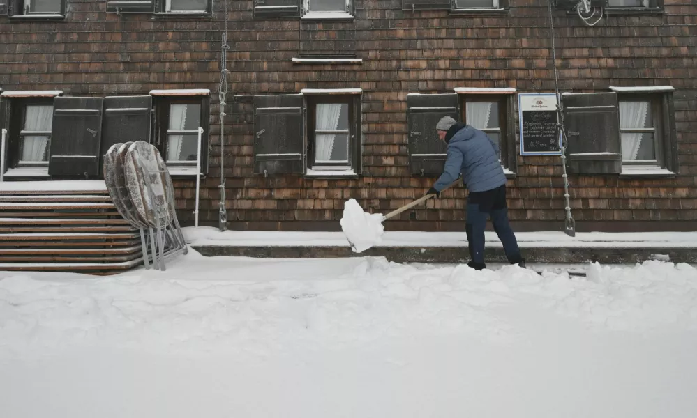 A worker clears snow in front of the "Muenchner Haus" mountain hut near the Zugspitze summit near Garmisch-Partenkirchen, Germany, September 12, 2024. REUTERS/Angelika Warmuth