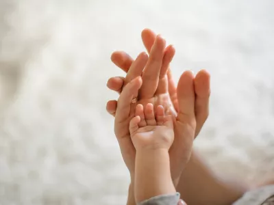 Close up of mother, father and baby join hands on the light background of room