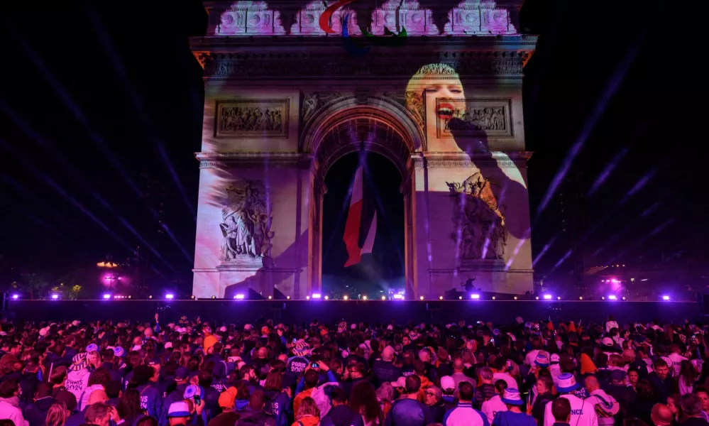 Attendees watch a recorded Lady Gaga performance projected on the Arc de Triomphe at the end of the parade of French athletes who competed in the Paris 2024 Olympic and Paralympic Games in Paris, France, September 14, 2024. ED JONES/Pool via REUTERS