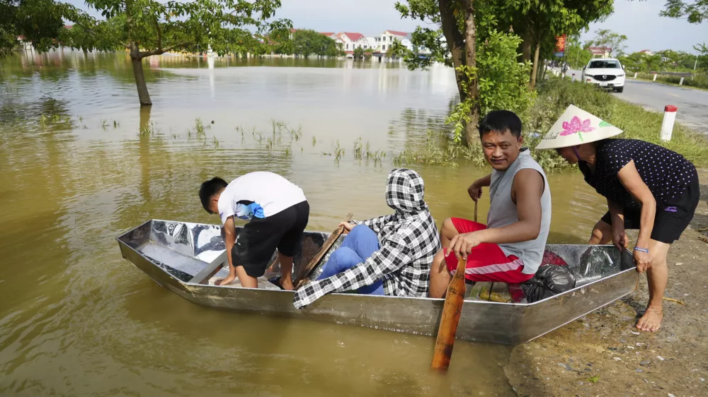 People sit on a boat to get to their flooded homes in the aftermath of Typhoon Yagi in An Lac village, Hanoi, Vietnam Friday, Sept. 13, 2024. (AP Photo/Hau Dinh)