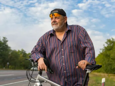 Outdoor portrait of a bearded senior man getting ready to ride on a bicycle / Foto: Yurikr