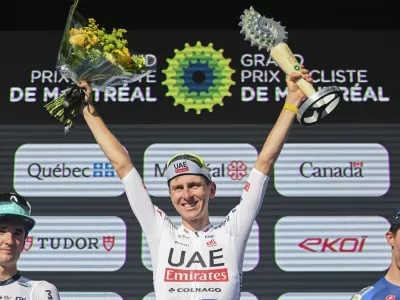 Tadej Pogacar, center, from Slovenia, raises his trophy after winning the Montreal Grand Prix cycling race in Montreal, Sunday, Sept. 15, 2024. (Graham Hughes/The Canadian Press via AP)