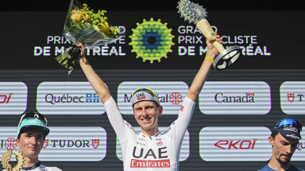 Tadej Pogacar, center, from Slovenia, raises his trophy after winning the Montreal Grand Prix cycling race in Montreal, Sunday, Sept. 15, 2024. (Graham Hughes/The Canadian Press via AP)