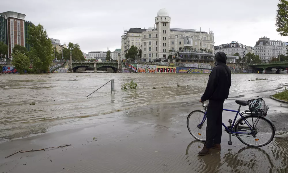 A cyclist looks at Donaukanal channel flood its banks at Urania observatory in central Vienna, Austria, Sunday, Sept. 15, 2024. (AP Photo/Heinz-Peter Bader)