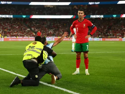 A pitch invader is detained as Portugal's Cristiano Ronaldo looks on during their Nations League match against Scotland, in Lisbon, Portugal, September 8. REUTERS/Pedro Nunes