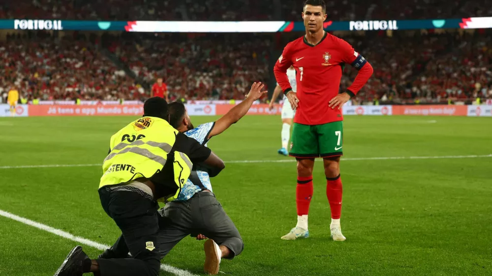 A pitch invader is detained as Portugal's Cristiano Ronaldo looks on during their Nations League match against Scotland, in Lisbon, Portugal, September 8. REUTERS/Pedro Nunes