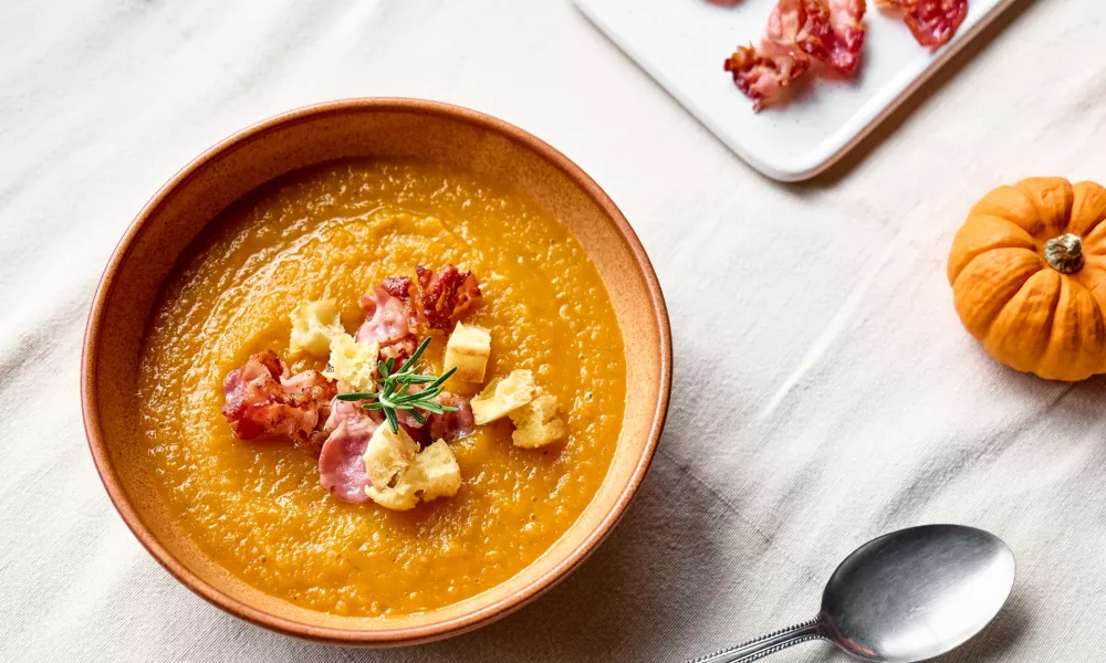 Pumpkin cream soup with roasted bacon and croutons in clay plate on the table with linen tablecloth. Autumn vegetable creamy soup puree. Healthy seasonal eating. / Foto: Ekaterina Fedulyeva