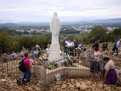 Pilgrims pray next to the statue of Virgin Mary on the Hill of appearance where it is believed that Virgin Mary showed herself and conveyed messages of peace to six children in Medjugorje, Bosnia, Thursday, Sept. 19, 2024. (AP Photo/Armin Durgut)