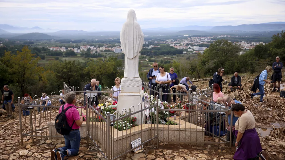 Pilgrims pray next to the statue of Virgin Mary on the Hill of appearance where it is believed that Virgin Mary showed herself and conveyed messages of peace to six children in Medjugorje, Bosnia, Thursday, Sept. 19, 2024. (AP Photo/Armin Durgut)