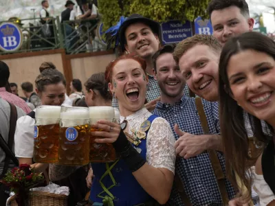 A waitress poses with guests at the Hofbraeuhaus beer tent on day one of the 189th 'Oktoberfest' beer festival in Munich, Germany, Saturday, Sept. 21, 2024. (AP Photo/Matthias Schrader)