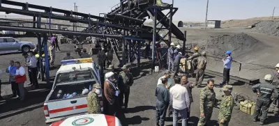 In this photo released by Iranian Red Crescent Society, rescue personnel, police officers and some other people gather around the site of a coal mine where methane leak sparked an explosion on Saturday, in Tabas, some 335 miles (540 kilometers) southeast of the capital Tehran, Iran, Sunday, Sept. 22, 2024. (Iranian Red Crescent Society, via AP)