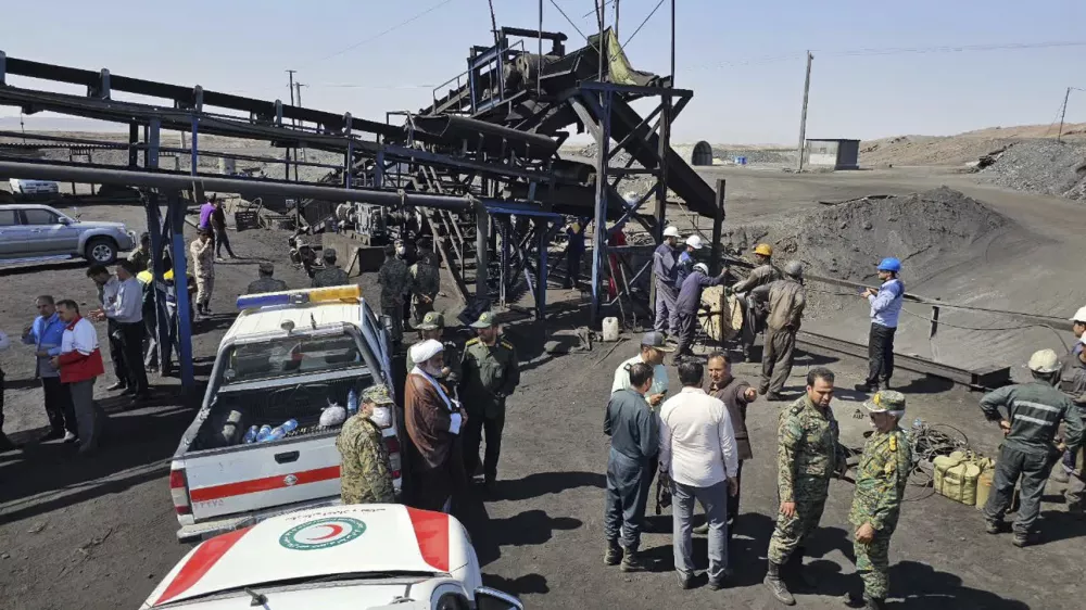 In this photo released by Iranian Red Crescent Society, rescue personnel, police officers and some other people gather around the site of a coal mine where methane leak sparked an explosion on Saturday, in Tabas, some 335 miles (540 kilometers) southeast of the capital Tehran, Iran, Sunday, Sept. 22, 2024. (Iranian Red Crescent Society, via AP)