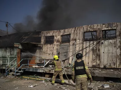 Firefighters work to extinguish a fire after a rocket, fired from Lebanon, hit a local municipality storage in Kiryat Shmona, northern Israel, Tuesday, Sept. 24, 2024. (AP Photo/Leo Correa)