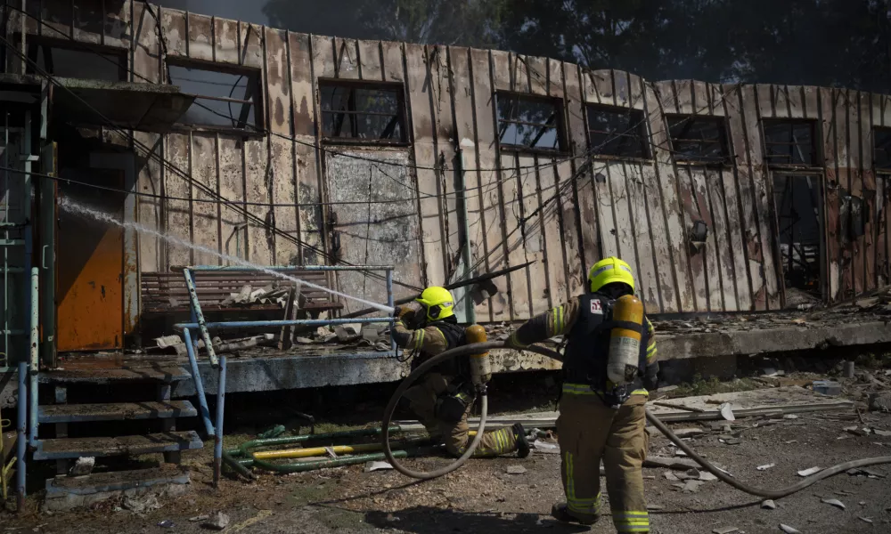 Firefighters work to extinguish a fire after a rocket, fired from Lebanon, hit a local municipality storage in Kiryat Shmona, northern Israel, Tuesday, Sept. 24, 2024. (AP Photo/Leo Correa)