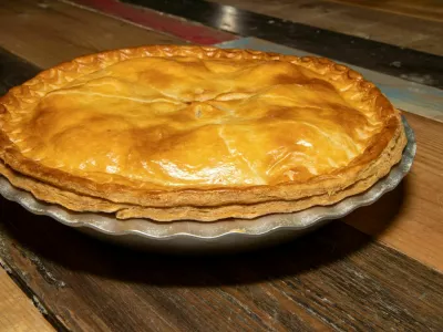 A delicious cooked meat pie showing the tasty meat pie and crust topping on a wooden kitchen table or work top / Foto: Duncan Cuthbertson