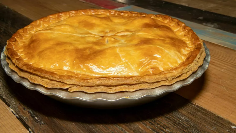 A delicious cooked meat pie showing the tasty meat pie and crust topping on a wooden kitchen table or work top / Foto: Duncan Cuthbertson