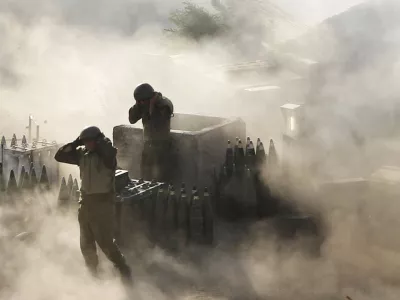 Israeli artillery soldiers are surrounded by smoke and dust as they fire across the border into southern Lebanon from a position on the frontier in Zaura, northern Israel, on July 12, 2006. (AP Photo/Oded Balilty, File)