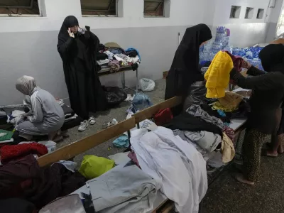 Volunteers distribute clothes to displayed women at a school in Beirut, Thursday, Sept. 26, 2024. (AP Photo/Bilal Hussein)