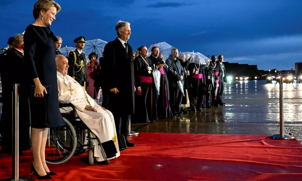 Pope Francis, flanked by Belgian King Philippe and Queen Mathilde, reacts after arriving at Melsbroek Military Air Base for a four-day apostolic journey, in Steenokkerzeel, Belgium, September 26, 2024. Vatican Media/­Handout via REUTERS  ATTENTION EDITORS - THIS IMAGE WAS PROVIDED BY A THIRD PARTY.