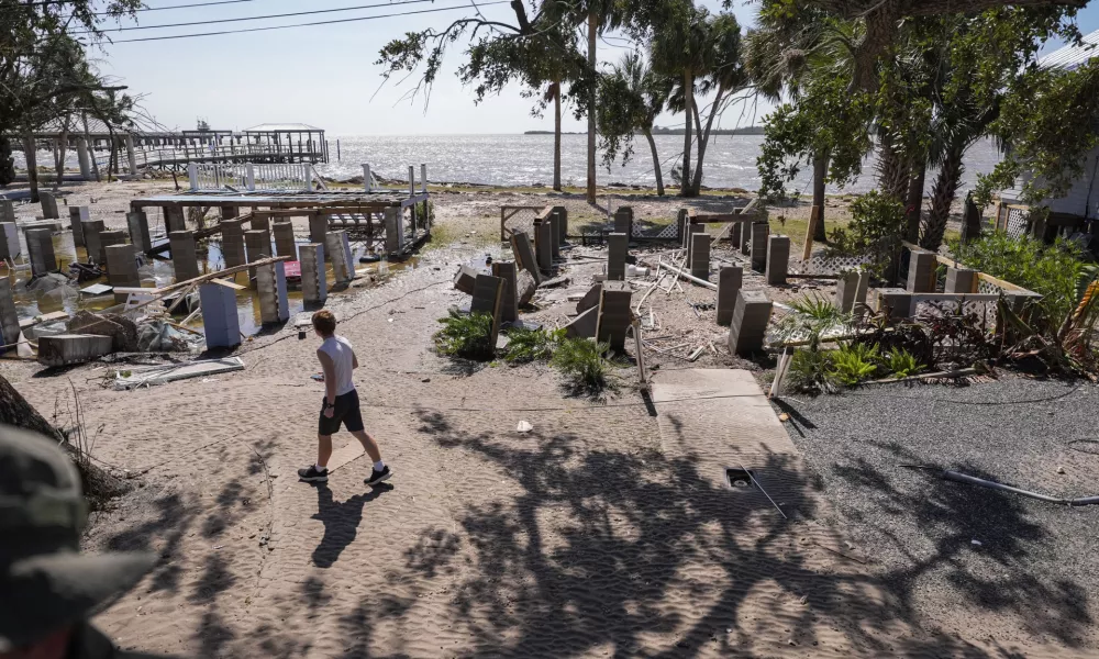 A person walks past building foundations along the water in the aftermath of Hurricane Helene, in Cedar Key, Fla., Friday, Sept. 27, 2024. (AP Photo/Gerald Herbert)