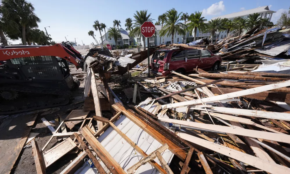 Workers clear debris in the aftermath of Hurricane Helene, in Cedar Key, Fla., Friday, Sept. 27, 2024. (AP Photo/Gerald Herbert)