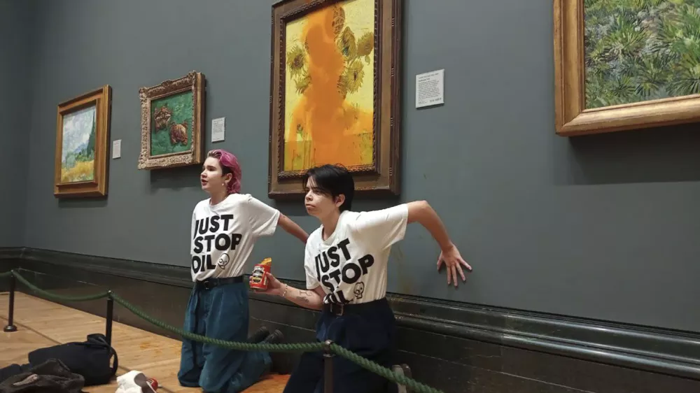 FILE - This photo provided by Just Stop Oil shows two protesters who have thrown tinned soup at Vincent Van Gogh's famous 1888 work Sunflowers at the National Gallery in London, Oct. 14, 2022. (Just Stop Oil via AP)