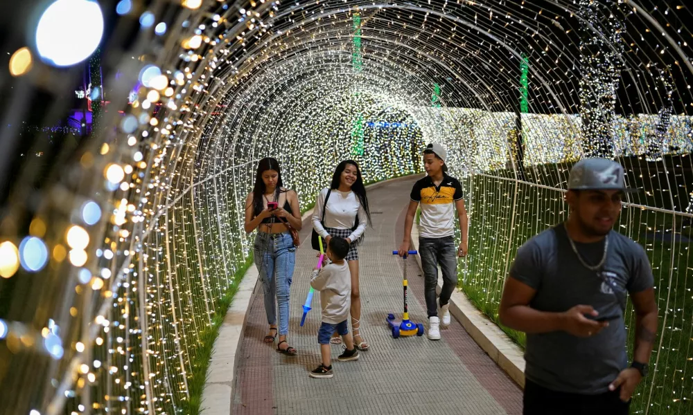 People walk through a tunnel made of Christmas lights in a public square, as the Christmas season kicks off as per a decree of Venezuela's President Nicolas Maduro, in Caracas, Venezuela October 1, 2024. REUTERS/Gaby Oraa