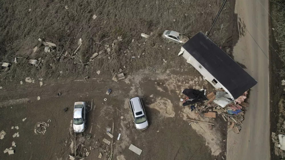 A destroyed mobile home and vehicles lay scattered across muddy land, Tuesday, Oct. 1, 2024, in Hendersonville, N.C., in the aftermath of Hurricane Helene. (AP Photo/Brittany Peterson)