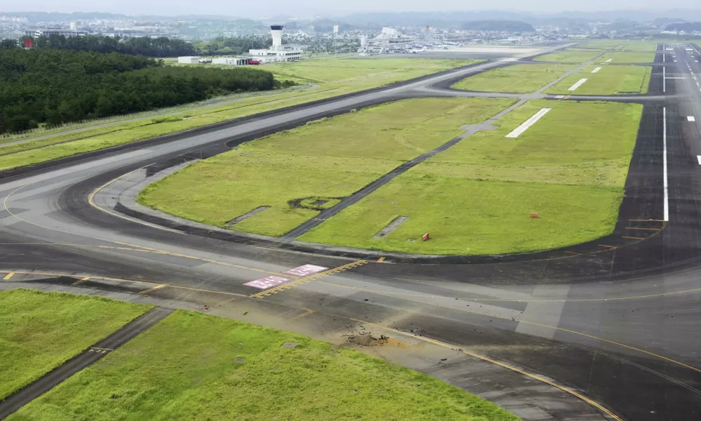 This photo taken from a Kyodo News helicopter shows part of a damaged taxiway, front, at Miyazaki Airport in southwestern Japan, Wednesday, Oct. 2, 2024, after an explosion was reported. (Kyodo News via AP)