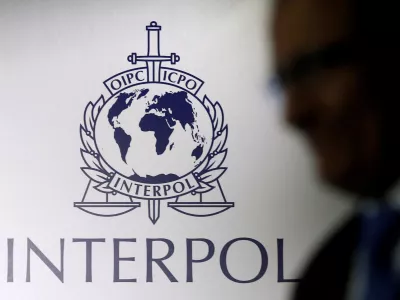 FILE PHOTO: A man passes an Interpol logo during the handing over ceremony of the new premises for Interpol's Global Complex for Innovation, a research and development facility, in Singapore September 30, 2014. REUTERS/Edgar Su//File Photo