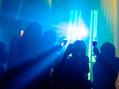 Silhouette image of people dance in disco night club to music from DJ on stage. New year night party and nightlife concept. / Foto: Nanostockk