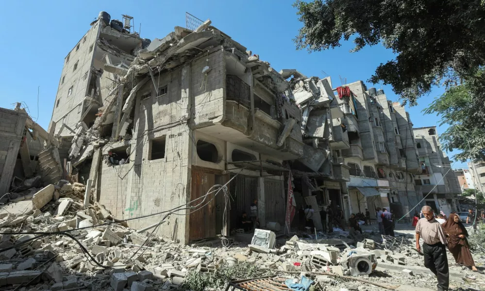 Palestinians walk past a house hit in an Israeli strike, amid the Israel-Hamas conflict, in Bureij refugee camp, in the central Gaza Strip, October 8, 2024. REUTERS/Ramadan Abed