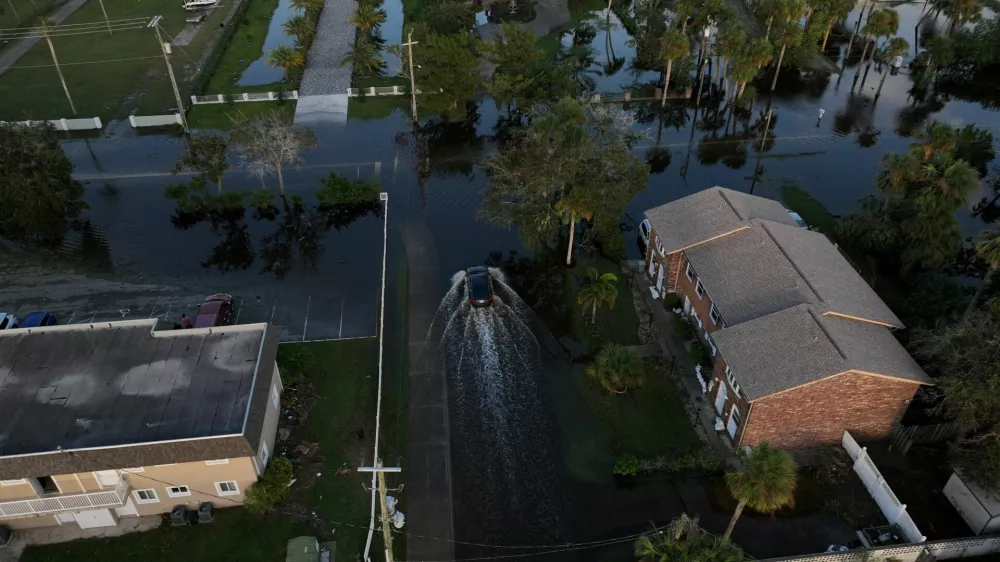 A drone view shows a car driving through a flooded street after Hurricane Milton made landfall in South Daytona, Florida, U.S., October 11, 2024. REUTERS/Ricardo Arduengo   TPX IMAGES OF THE DAY