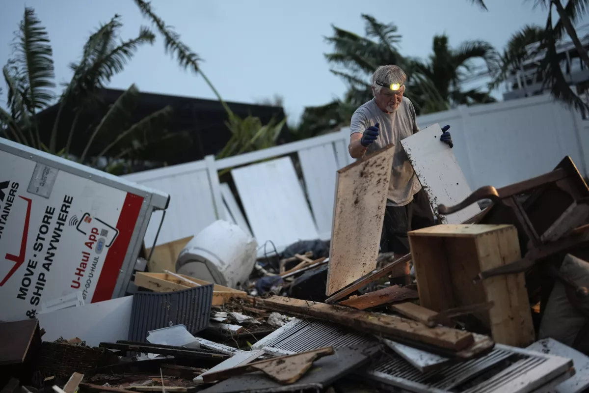 Robert Turick, 68, works to clear household debris that Hurricane Milton storm surge swept from other properties into his canal-facing back yard, in Englewood, Fla., Friday, Oct. 11, 2024. Turick, whose family has owned the home for more than 25 years, said it had never flooded until 2022's Hurricane Ian, but since then, it has flooded in three more hurricanes, each bringing higher water levels than the last. A small positive, said Turick, is that he hadn't yet begun repairs after Hurricane Helene's 3-foot flood waters before Hurricane Milton brought five feet of flooding. (AP Photo/Rebecca Blackwell)